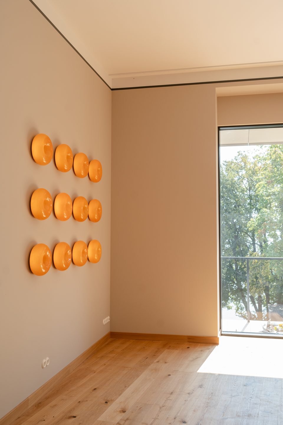 Living room with oak floor and a wall of orange lamps, finished by Expat Mates in Elektrėnai